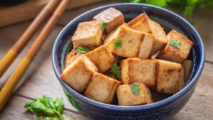 Cubes de tofu grillés avec des feuilles de coriandre dans un bol bleu.