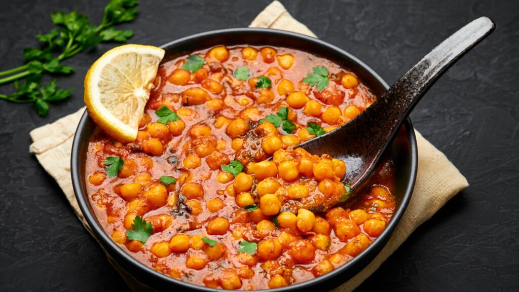 Un bol de curry de pois chiches garni de coriandre et de citron.