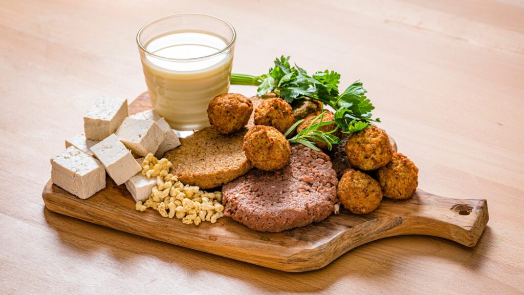 Assortiment de substituts végétaliens tels que le tofu, les galettes végétales, et les falafels, pour une alimentation végétale riche en protéines.