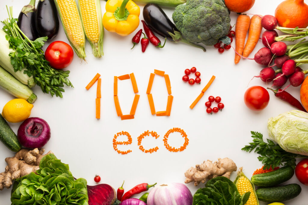 Le texte "100% éco" écrit avec des carottes et des lentilles, entouré de légumes frais, pour illustrer une alimentation écologique et bonne pour la santé.