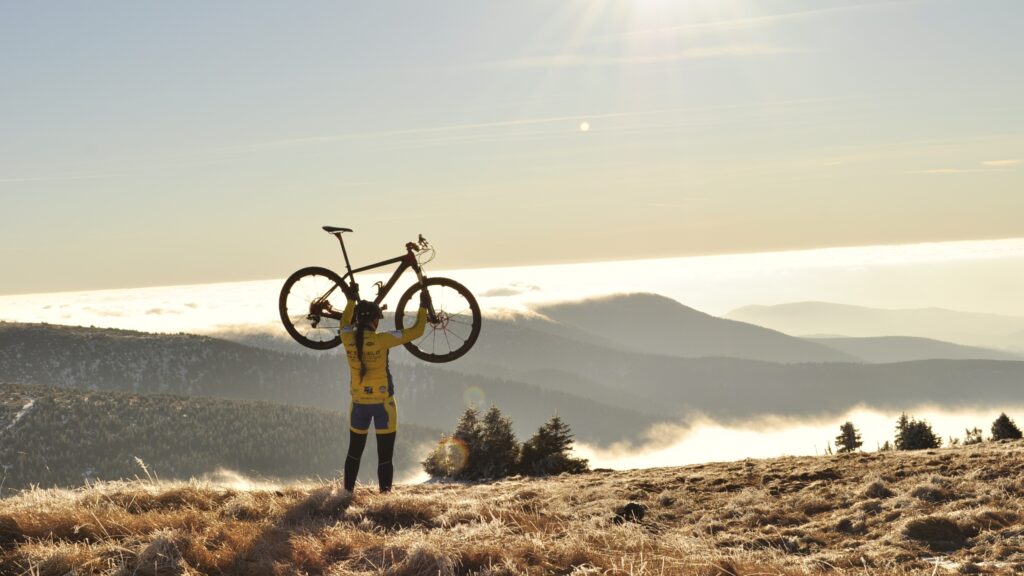 Un cycliste végétarien triomphant au sommet d'une montagne, soulevant son vélo au-dessus de sa tête.