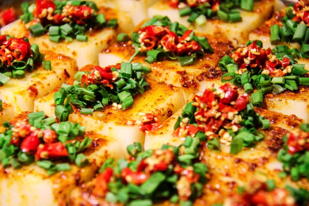 Assiette de tempeh grillé épicé avec garniture de piments rouges et ciboulette.