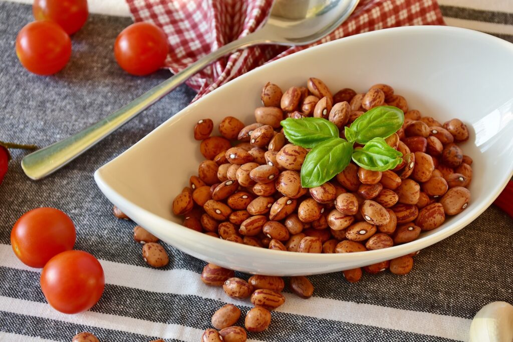 Bol de haricots pinto sur une table entourée de tomates cerises, montrant la richesse des protéines végétales souvent ignorée dans les remarques anti-végétariennes.