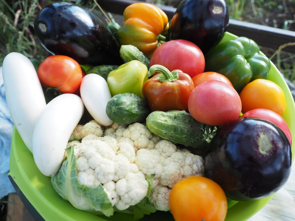 Assortiment de légumes frais dans un bol vert, mettant en valeur la variété de l'alimentation végétarienne face aux remarques anti-végétariennes.