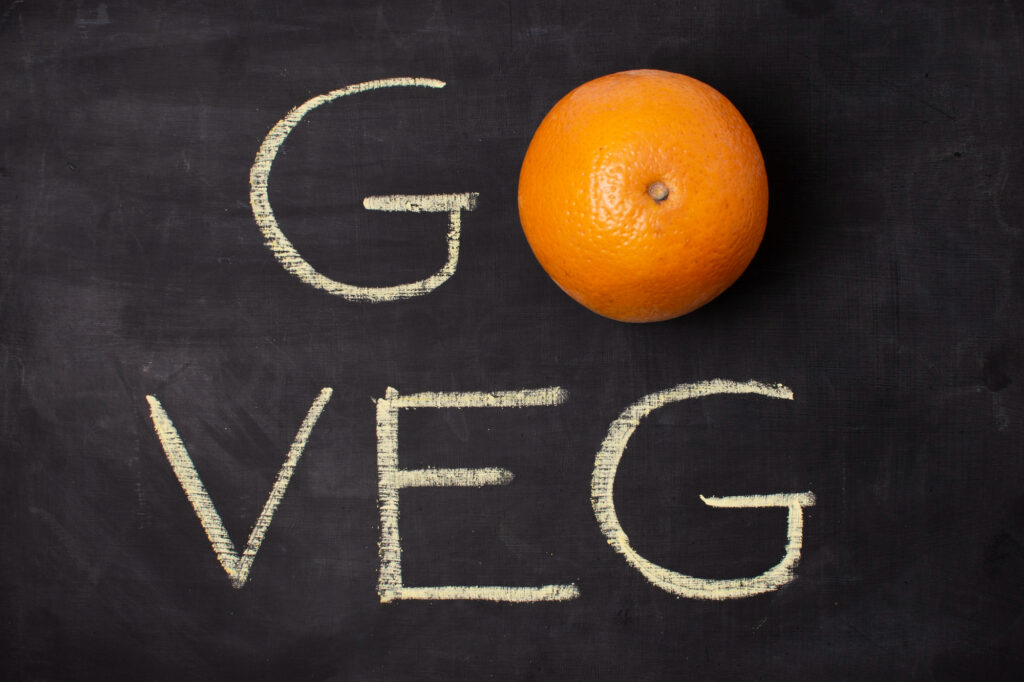 Une orange sur un tableau noir avec "Go Veg" inscrit à la craie, symbolisant une alternative à la consommation de viande.